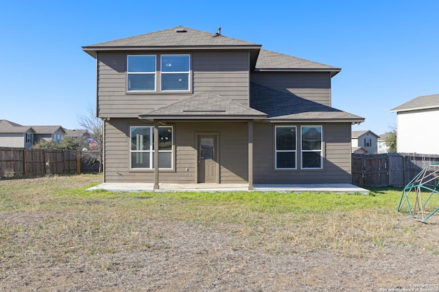 rear view of house with a patio area, a yard, and a fenced backyard