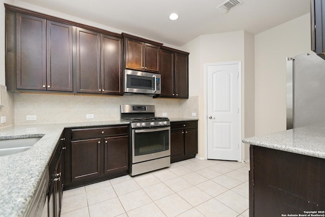 kitchen featuring visible vents, dark brown cabinetry, appliances with stainless steel finishes, light tile patterned flooring, and decorative backsplash