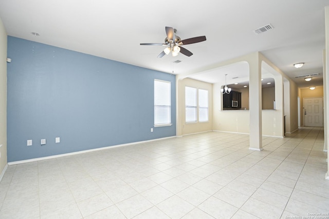 empty room featuring visible vents, baseboards, light tile patterned flooring, and ceiling fan with notable chandelier