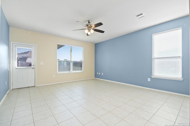 empty room featuring light tile patterned floors, visible vents, baseboards, and a ceiling fan