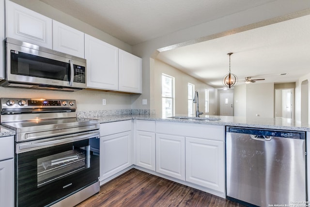 kitchen featuring dark wood-type flooring, a sink, light stone counters, appliances with stainless steel finishes, and white cabinets