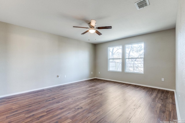 empty room with visible vents, baseboards, a ceiling fan, and dark wood-style flooring