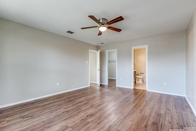 unfurnished room featuring ceiling fan, wood finished floors, visible vents, and baseboards