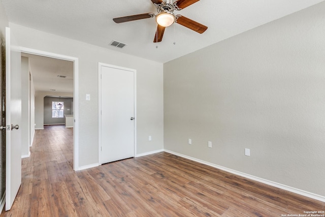 unfurnished bedroom featuring visible vents, ceiling fan, baseboards, and wood finished floors