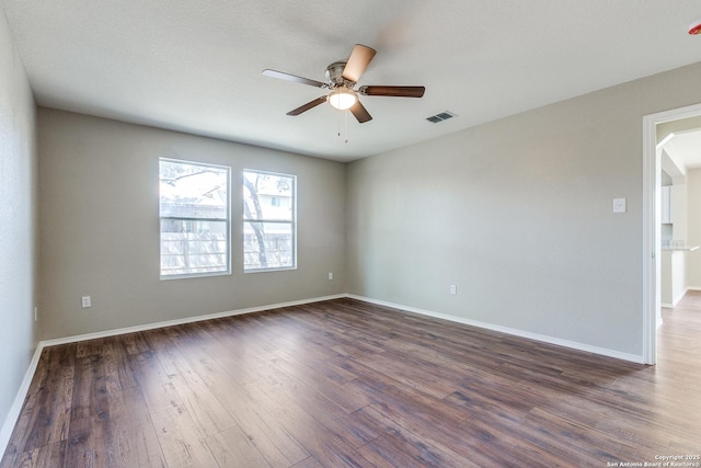 unfurnished room with a ceiling fan, dark wood-type flooring, baseboards, and visible vents