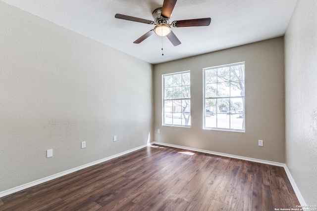 unfurnished room featuring a textured wall, ceiling fan, baseboards, and dark wood-style flooring