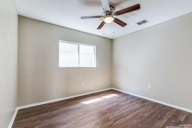 spare room featuring a ceiling fan, baseboards, visible vents, and dark wood-style flooring