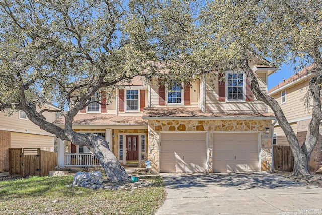 view of front of property with stone siding, a porch, concrete driveway, and fence