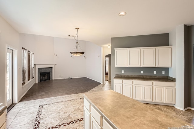 kitchen featuring baseboards, a tiled fireplace, pendant lighting, recessed lighting, and white cabinetry