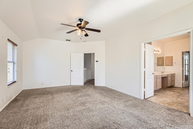 unfurnished bedroom with visible vents, baseboards, ensuite bath, vaulted ceiling, and light colored carpet