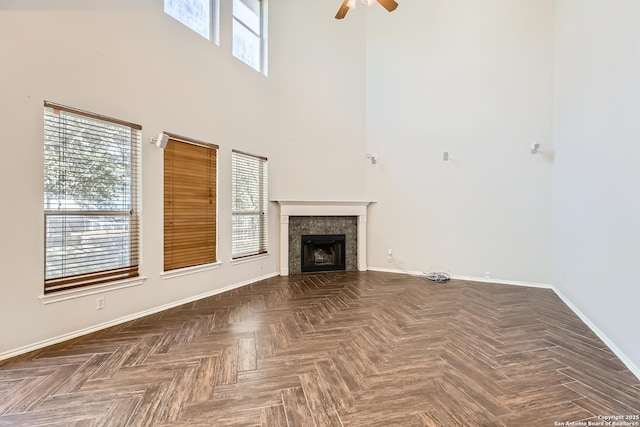 unfurnished living room with a healthy amount of sunlight, a fireplace, and a towering ceiling