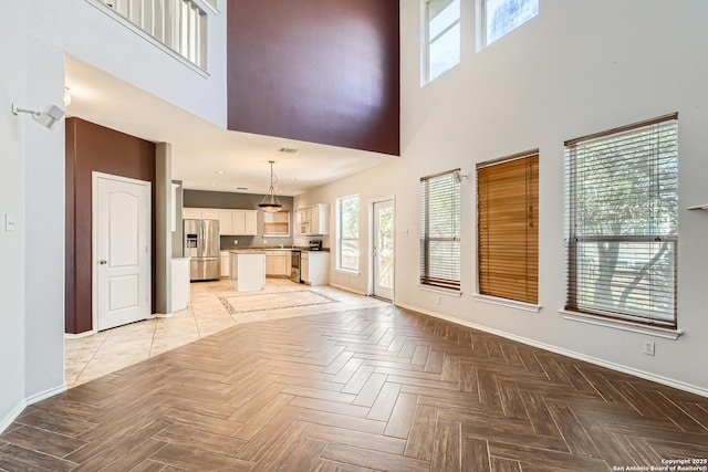 unfurnished living room featuring a high ceiling and baseboards