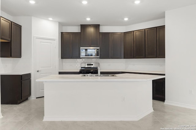 13210 Club House Blvd, San Antonio, TX 78221 - kitchen featuring appliances with stainless steel finishes, an island with sink, dark brown cabinetry, backsplash, and recessed lighting