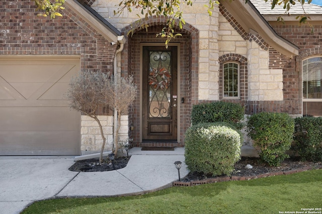 entrance to property featuring an attached garage, brick siding, and stone siding