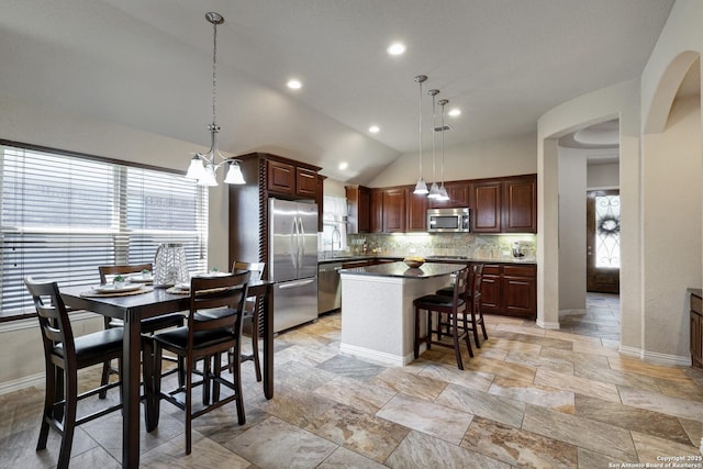 kitchen featuring a breakfast bar, a sink, a kitchen island, backsplash, and appliances with stainless steel finishes