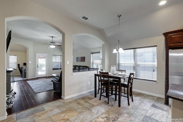 dining space featuring visible vents, ceiling fan, baseboards, vaulted ceiling, and a textured ceiling