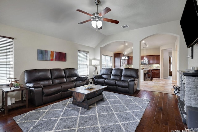 living room featuring visible vents, hardwood / wood-style flooring, arched walkways, lofted ceiling, and ceiling fan