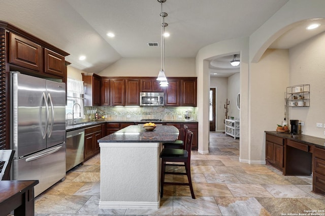 kitchen featuring tasteful backsplash, visible vents, a center island, appliances with stainless steel finishes, and a sink