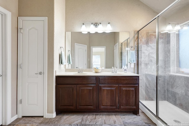 full bathroom featuring double vanity, a stall shower, and a sink