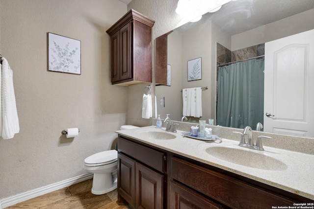 bathroom with double vanity, curtained shower, toilet, and a sink