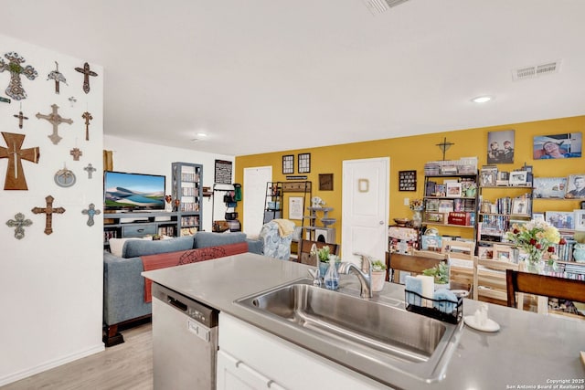 kitchen with visible vents, open floor plan, stainless steel dishwasher, white cabinetry, and a sink