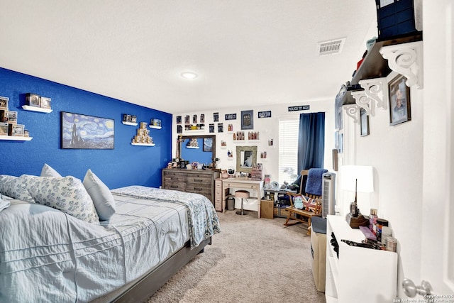 bedroom featuring light carpet, visible vents, and a textured wall