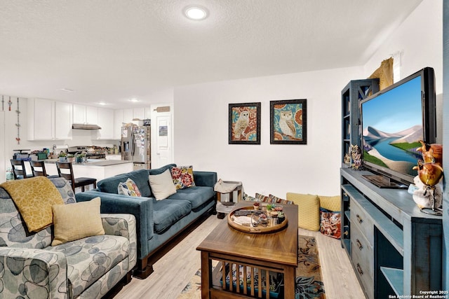 living room with recessed lighting, a textured ceiling, and light wood-style flooring