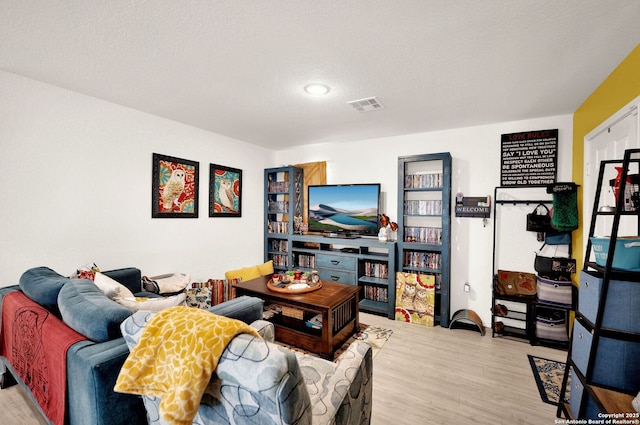 living room with visible vents, a textured ceiling, and wood finished floors