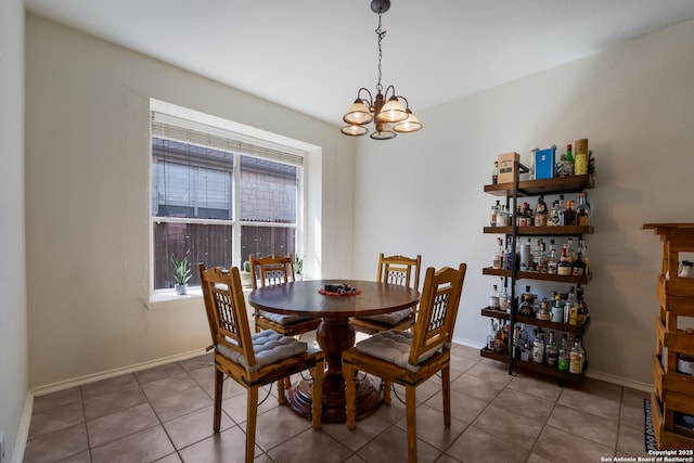 tiled dining space featuring baseboards and a chandelier