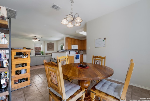 dining space with light tile patterned flooring, visible vents, ceiling fan with notable chandelier, and baseboards