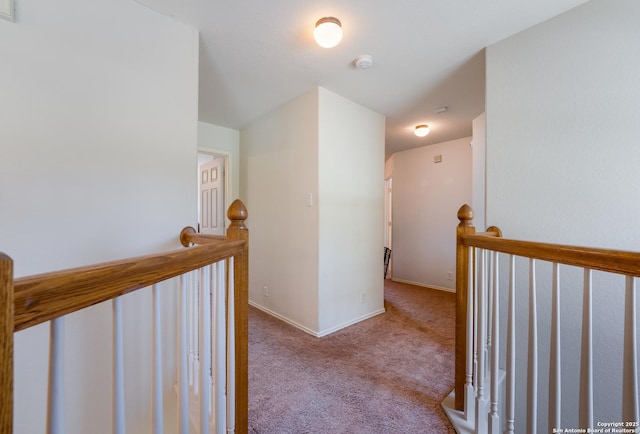 hallway with carpet flooring, an upstairs landing, and baseboards