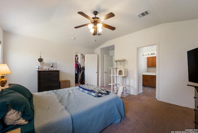 carpeted bedroom with visible vents, a walk in closet, connected bathroom, lofted ceiling, and ceiling fan