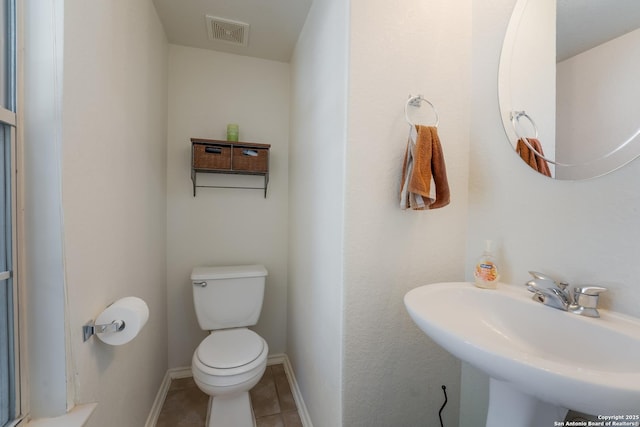 bathroom with visible vents, baseboards, toilet, tile patterned floors, and a sink