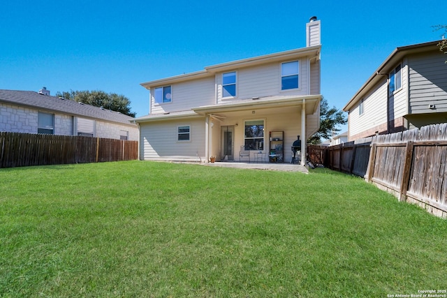 rear view of property featuring a patio area, a lawn, a chimney, and a fenced backyard