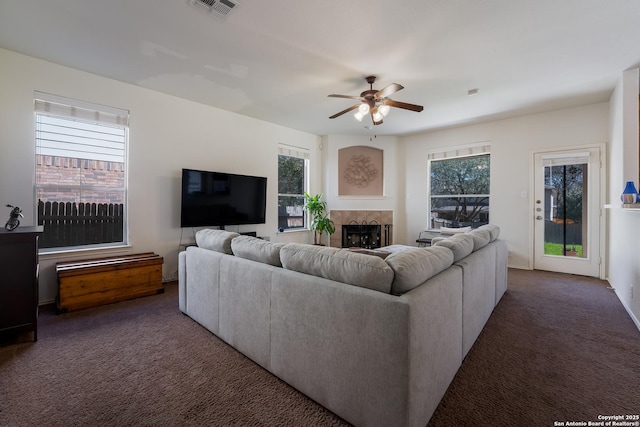 carpeted living area featuring visible vents, ceiling fan, and a tile fireplace