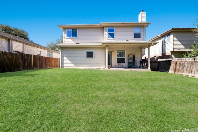 rear view of property featuring a fenced backyard, a patio area, a chimney, and a yard