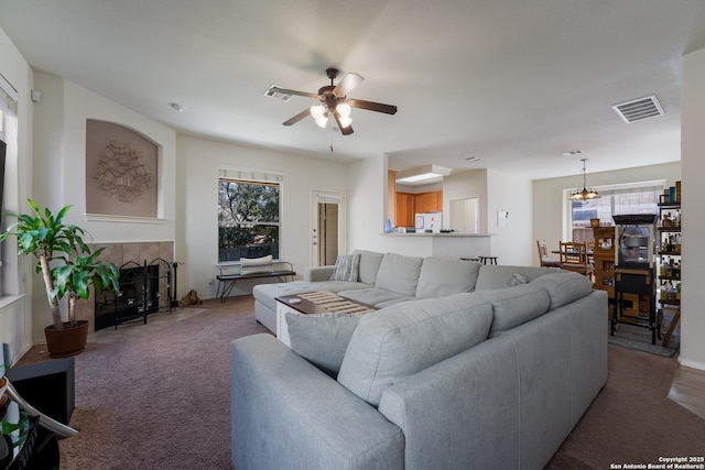 carpeted living room featuring visible vents, a fireplace, and a ceiling fan