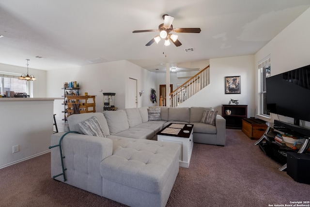 living room with visible vents, ceiling fan with notable chandelier, stairway, and carpet