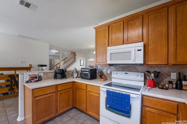 kitchen with white appliances, light tile patterned floors, visible vents, a peninsula, and light countertops