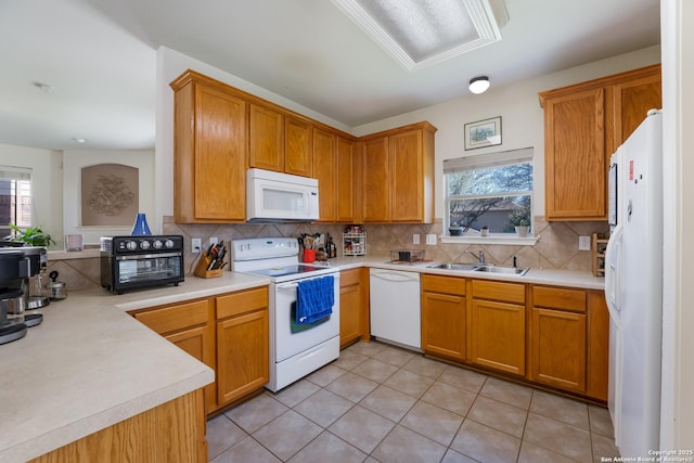 kitchen featuring light countertops, light tile patterned floors, decorative backsplash, white appliances, and a sink