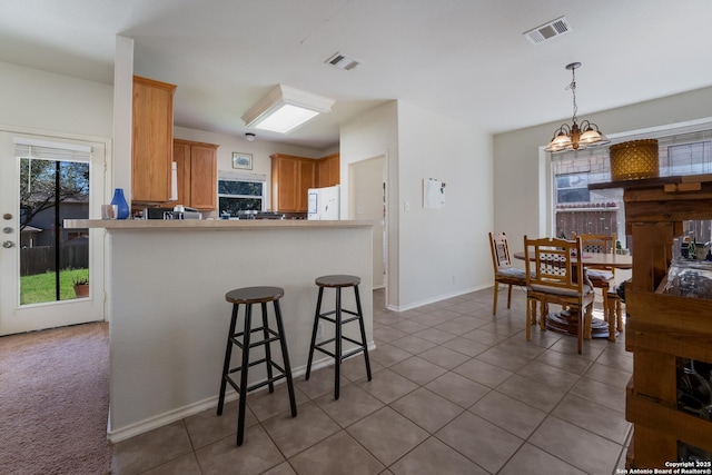 kitchen with fridge, visible vents, a peninsula, and pendant lighting