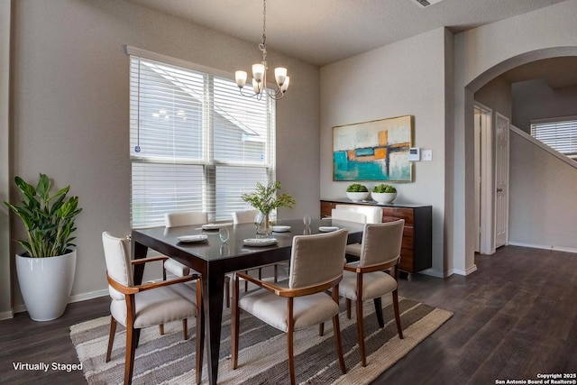 dining room with arched walkways, dark wood-style flooring, healthy amount of natural light, and baseboards