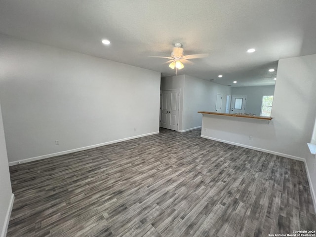 unfurnished living room featuring recessed lighting, ceiling fan, baseboards, and dark wood-style flooring