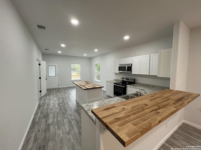 kitchen with visible vents, wood counters, a kitchen island, stainless steel appliances, and dark wood-style flooring