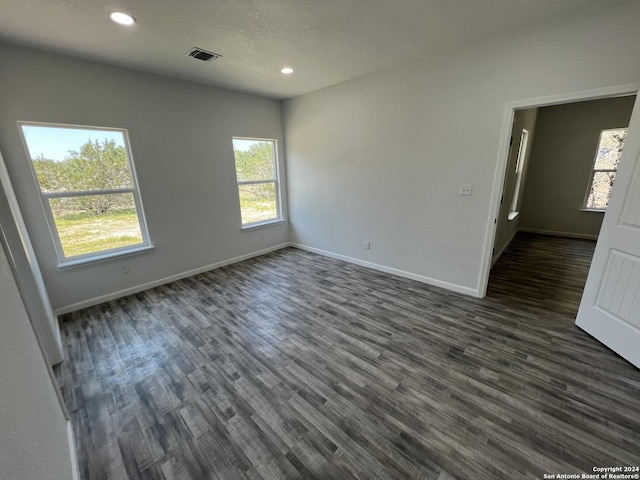 empty room featuring visible vents, a textured ceiling, recessed lighting, baseboards, and dark wood-style flooring