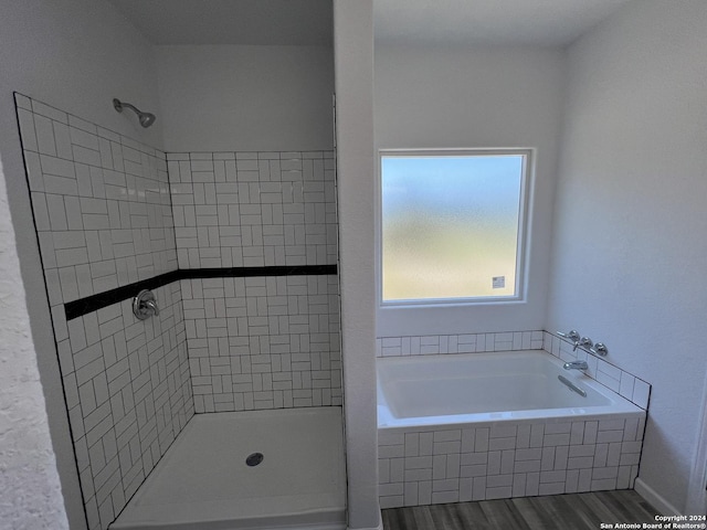 bathroom featuring a bath, a shower stall, and wood finished floors