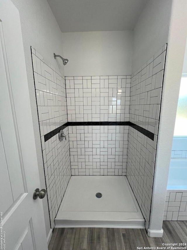 full bath featuring a tile shower and wood finished floors