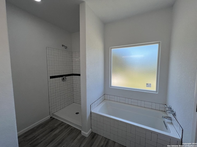 bathroom featuring baseboards, tiled shower, wood finished floors, and a bath