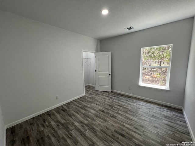 spare room featuring visible vents, baseboards, and dark wood finished floors