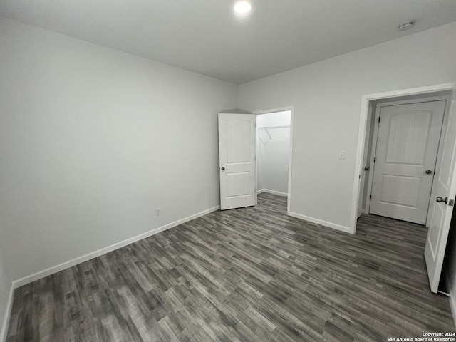 unfurnished bedroom featuring a closet, baseboards, and dark wood-style flooring